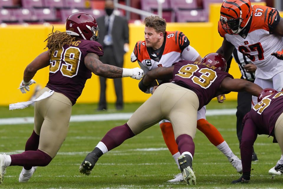 Cincinnati Bengals quarterback Joe Burrow (9) looses his helmet as he is tackled by Washington Football Team defensive tackle Jonathan Allen (93) during the first half of an NFL football game, Sunday, Nov. 22, 2020, in Landover. (AP Photo/Susan Walsh)