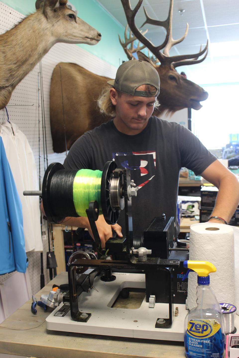 Mad Kingz Tackle employee Will Lamiman, 17, strings a reel during a quiet moment in the shop on July 15.