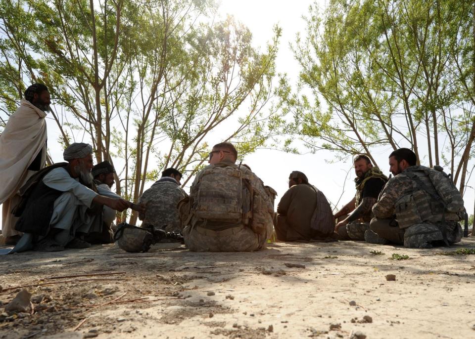 A Human Terrain Team consisting of U.S. Army soldiers and civilians, along with an Afghan translator, meet with local citizens of a village near Kandahar Air Field in Afghanistan on April 3, 2013. The teams include military and civilian personnel who interact with residents to gain knowledge, so they can aid in creating a stable environment and learn how to conduct future military and humanitarian operations.
