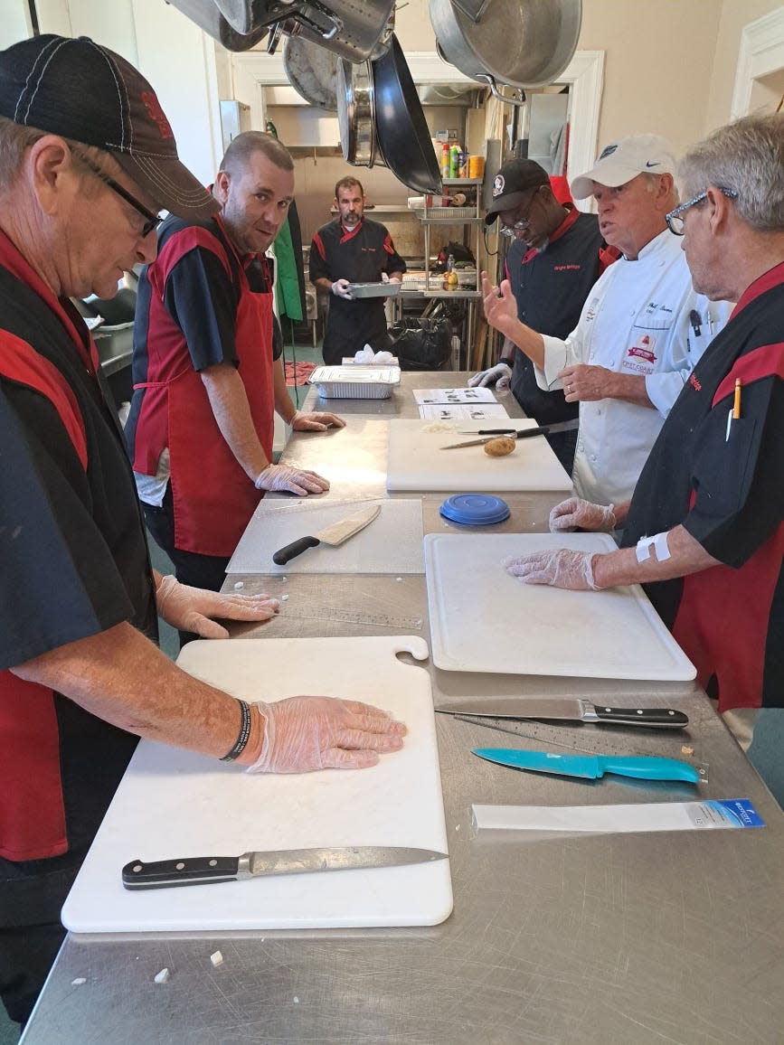 Chef Phil Brown, in white, trains the men in the Fresh Start program on knife skills.