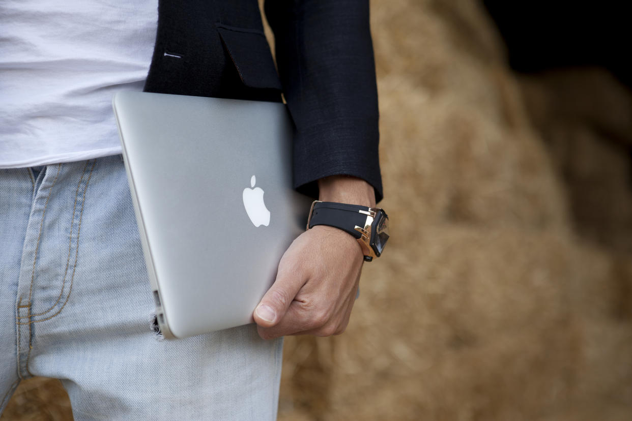 A man carrying an Apple MacBook. (PHOTO: Getty Images)