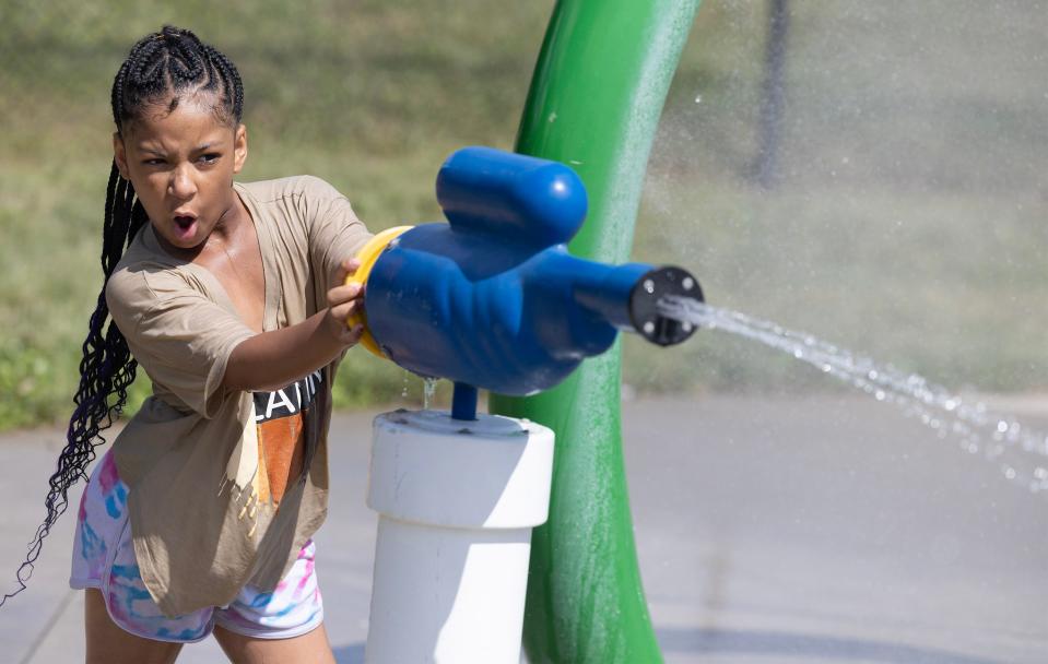 Adrielle Parker, 8, shoots a water cannon Thursday, July 13, 2023, a warm day at Crenshaw Park spray park in Canton.