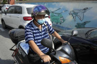 A man wearing a mask rides past wall mural depicting military helicopter and fighter jets in Pingtan in eastern China's Fujian Province, Sunday, Aug. 7, 2022. Taiwan said Saturday that China's military drills appear to simulate an attack on the self-ruled island, after multiple Chinese warships and aircraft crossed the median line of the Taiwan Strait following U.S. House Speaker Nancy Pelosi's visit to Taipei that infuriated Beijing. (AP Photo/Ng Han Guan)