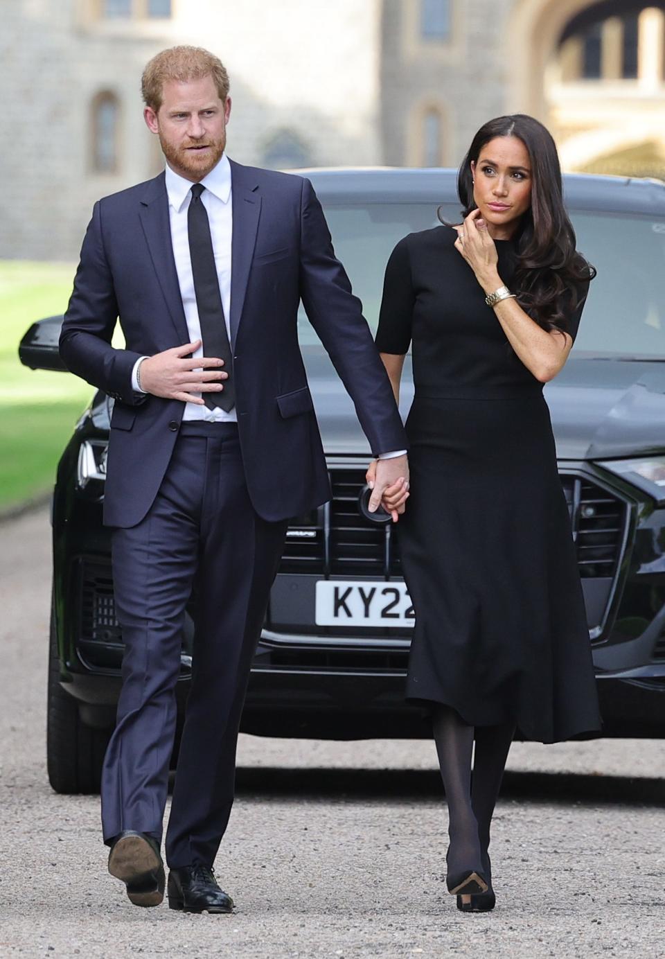 Prince Harry and Meghan Markle walk in front of Windsor Castle.