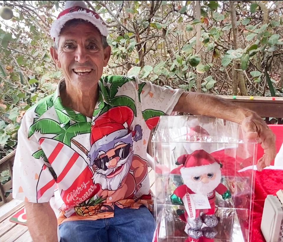 George Trosset getting ready for the 14th Surfing Santa event Christmas Eve tin Cocoa Beach, sitting with the Surfing Santa that went into space.