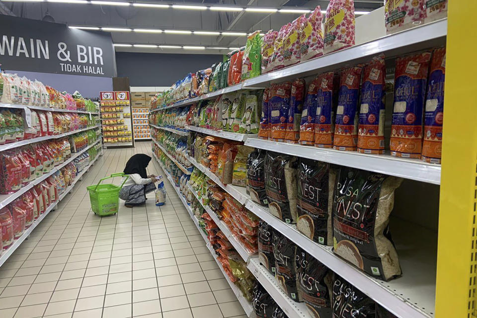 A customer looks at products along a row with imported rice in a supermarket in Kuala Lumpur, Malaysia, Tuesday, Oct. 3, 2023. Malaysia's government has reassured the country that enough rice is available and urged people not to hoard locally produced rice after recent panic-buying led to empty shelves in supermarkets and grocery stores nationwide. (AP Photo/Syawalludin Zain)