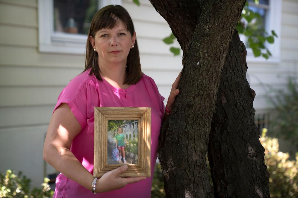 Jessica Riester Hart stands near a sweetgum tree in her yard that her daughter Allie liked to climb as she holds a photo of her daughter, Thursday, Sept. 14, 2023, in Washington. 5-year-old Allie Hart was struck and killed in 2021 by a driver while riding her bicycle in a crosswalk near their home.