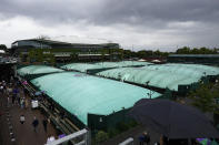 People walk past the covered courts after rain stopped play on day two of the Wimbledon tennis championships in London, Tuesday, July 4, 2023. (AP Photo/Alastair Grant)