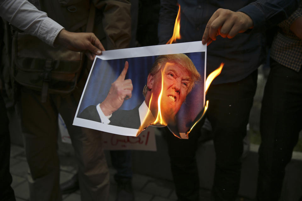 FILE - In this May 9, 2018, file photo, Iranian demonstrators burn a picture of the U.S. President Donald Trump during a protest in front of the former U.S. Embassy in Tehran, Iran. (AP Photo/Vahid Salemi, File)