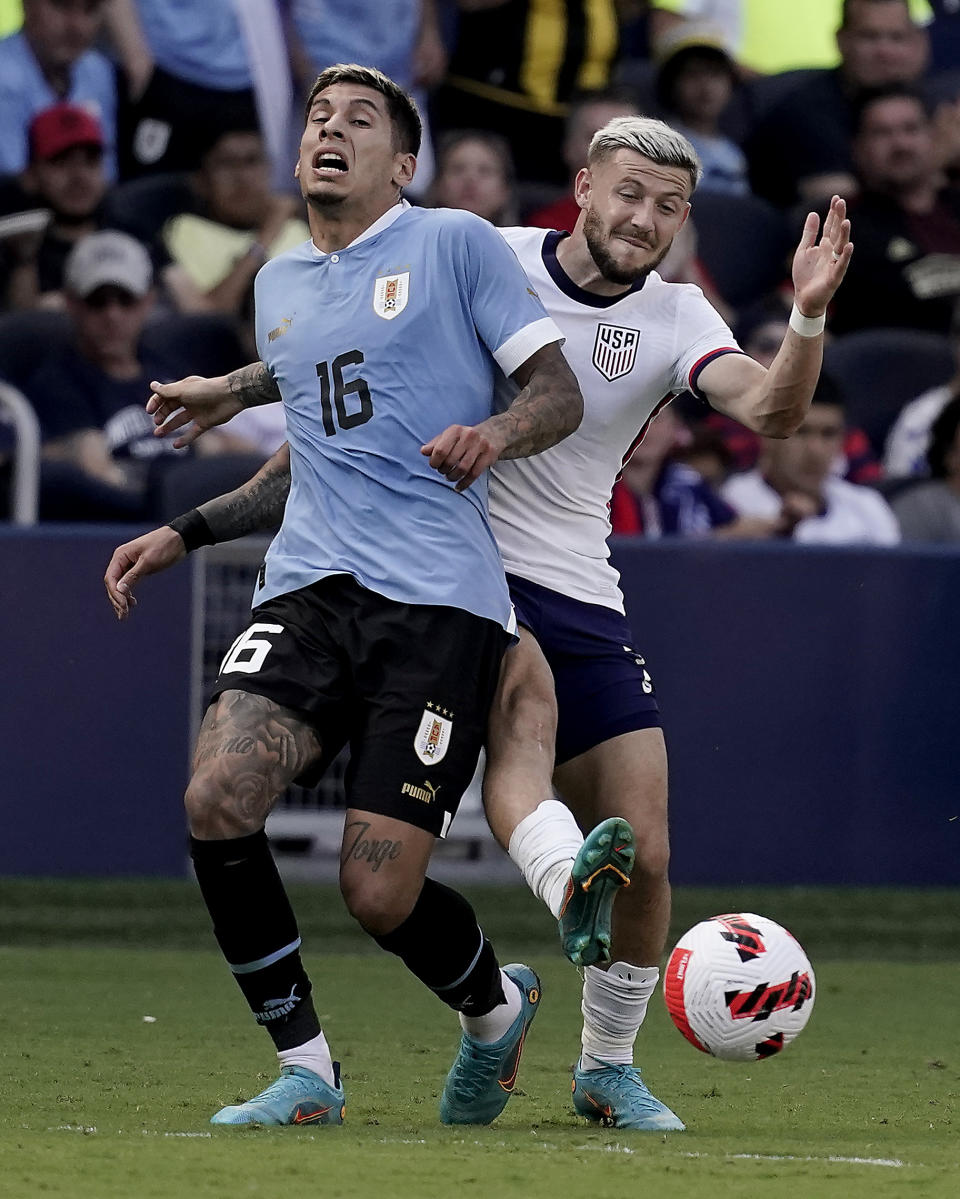 USA forward Paul Arriola, right, kicks the ball past Uruguay defender Mathias Olivera (16) during the second half of an international friendly soccer match Sunday, June 5, 2022, in Kansas City, Kan. The match ended in a 0-0 tie. (AP Photo/Charlie Riedel)