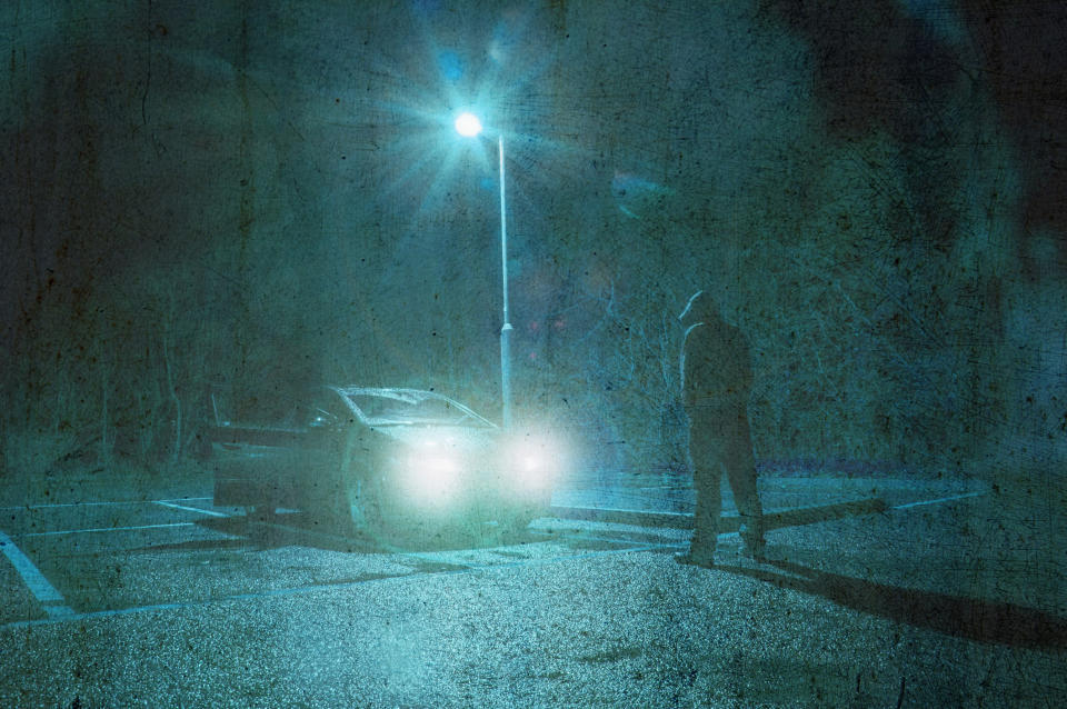 man stands in front of car in parking lot