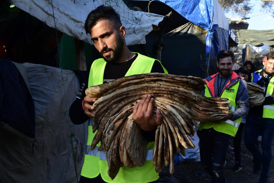 Un hombre carga pan en el campamento para refugiados Moria, en la isla Lesbos, Grecia, el lunes 24 de febrero de 2020. (AP Foto/Michael Varaklas)