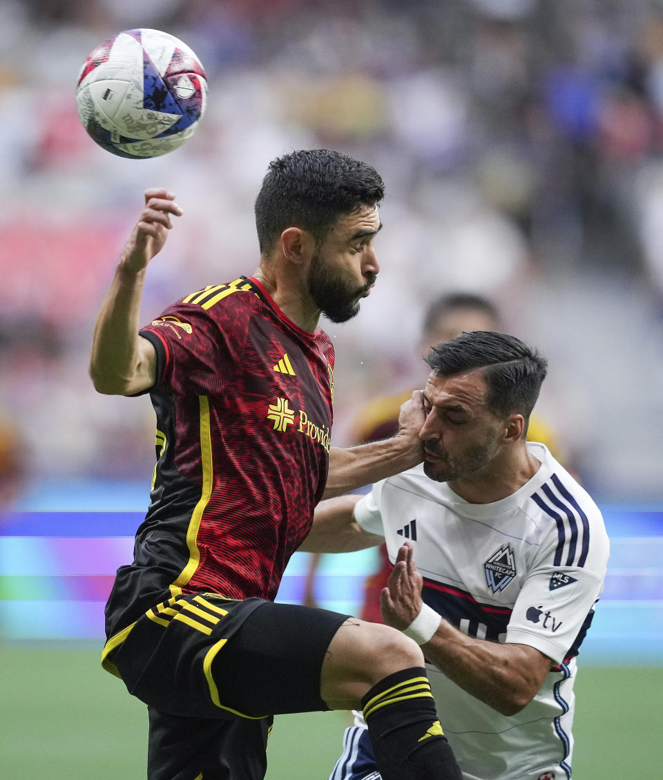 Seattle Sounders' Alex Roldan, left, and Vancouver Whitecaps' Luis Martins vie for the ball during the first half of an MLS soccer match Saturday, July 8, 2023, in Vancouver, British Columbia. (Darryl Dyck/The Canadian Press via AP)