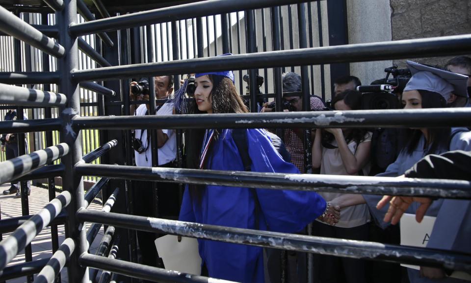 A member of the group Border Dreamers clasp the hand of colleague as she leads the way through the metal turnstyle into the United States where they planned to ask for asylum Monday, March 10, 2014, in Tijuana, Mexico. (AP Photo/Lenny Ignelzi)