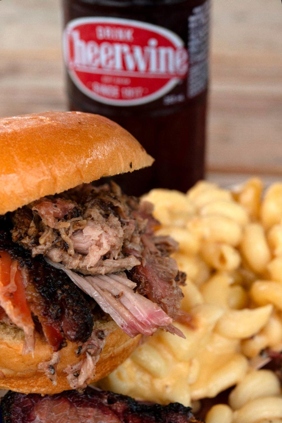 A pulled pork sandwich with a side of smoked mac and cheese and a cold Cheerwine served up at Dampf Good Barbecue in Cary.