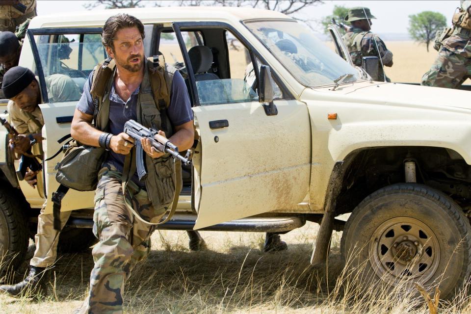 Gerard Butler runs out of a vehicle with a machine gun