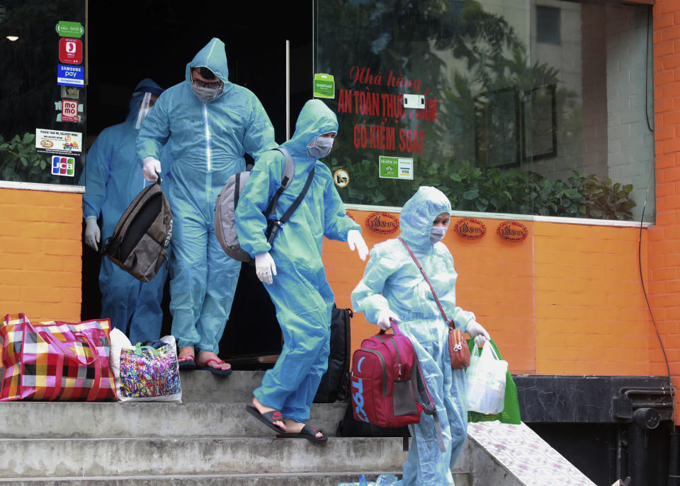 People walk toward an ambulance to be driven to a hospital for quarantine relating to a suspected COVID-19 case in Hanoi, Vietnam, Wednesday, July 29, 2020. Vietnam intensifies protective measures as the number of locally transmissions, starting at a hospital in the popular beach city of Da Nang, keeps increasing since the weekend. (AP Photo/Hau Dinh)