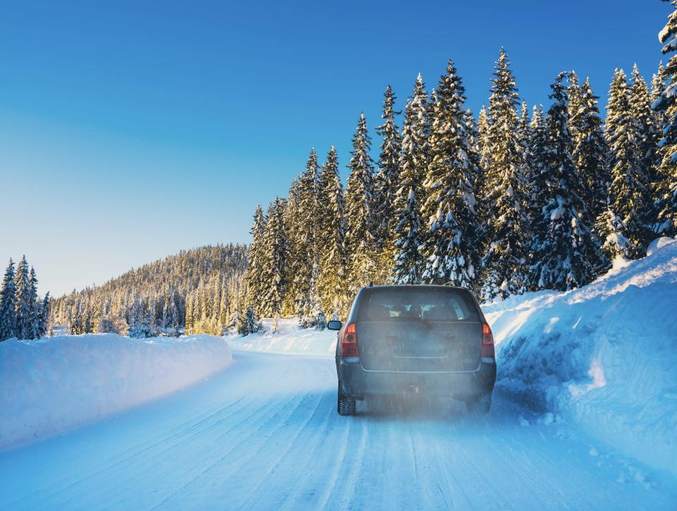 Car getting stuck in snow on road with trees around it