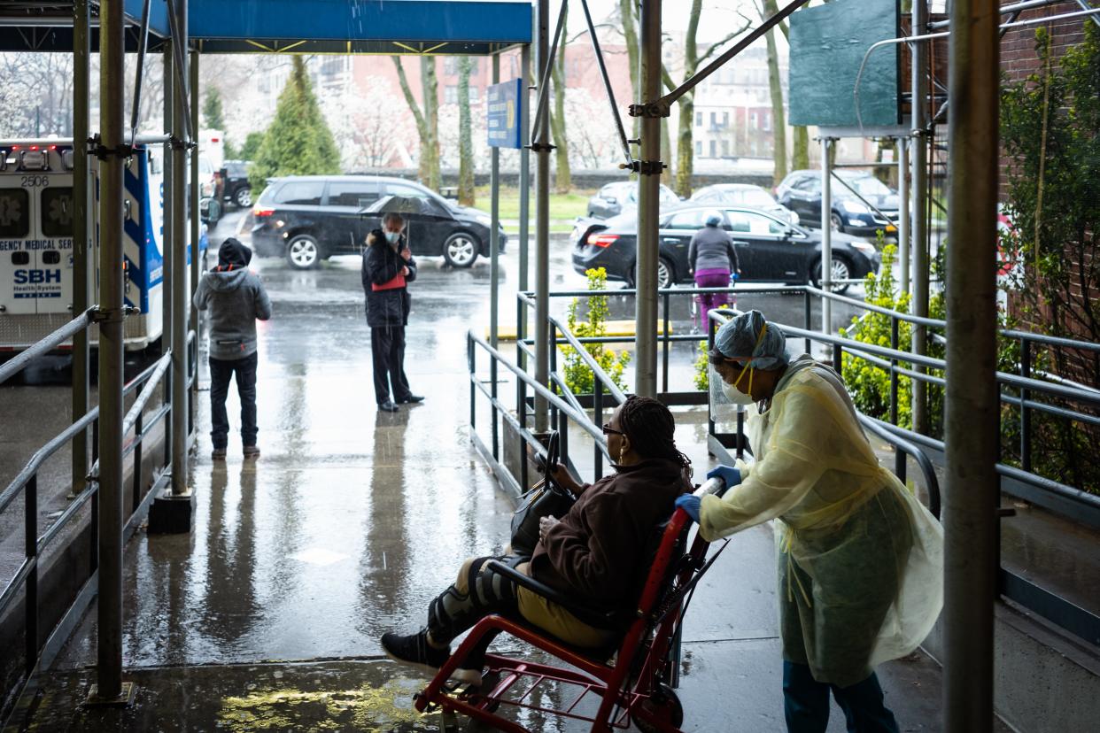 A staff member pushes a patient in a wheelchair at St Barnabas Hospital on 23 March, 2020 in the Bronx borough of New York City.  (Getty Images)
