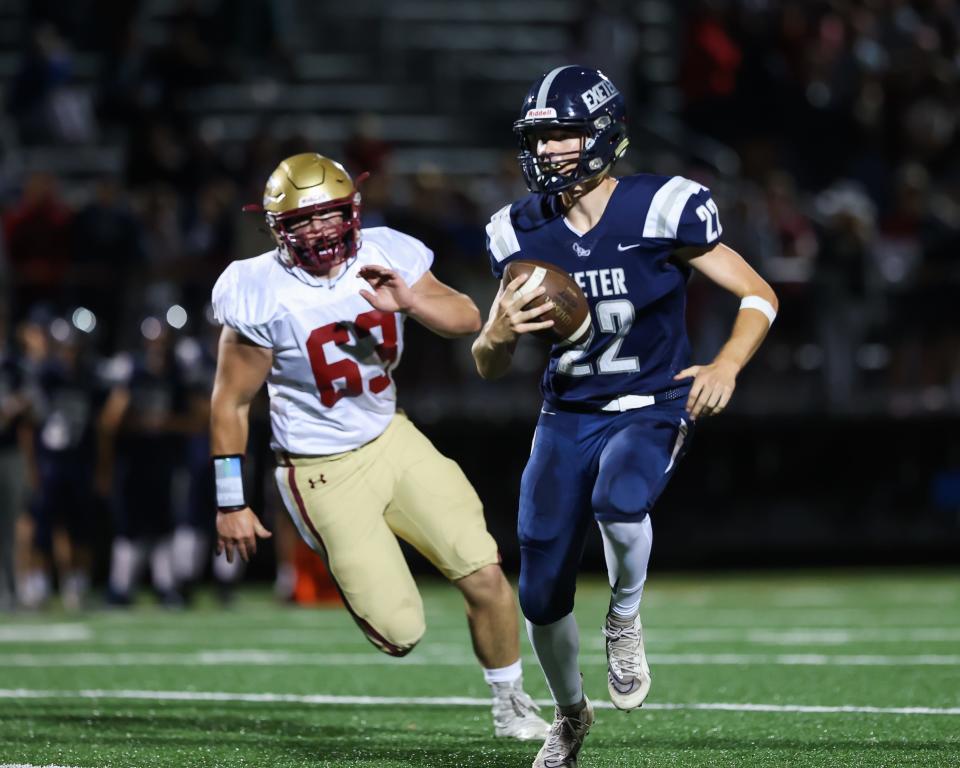 Exeter's quarterback Evan Pafford scrambles as Porstmouth/Oyster River's Kody Ricard pursues during the season-opening game in Exeter.