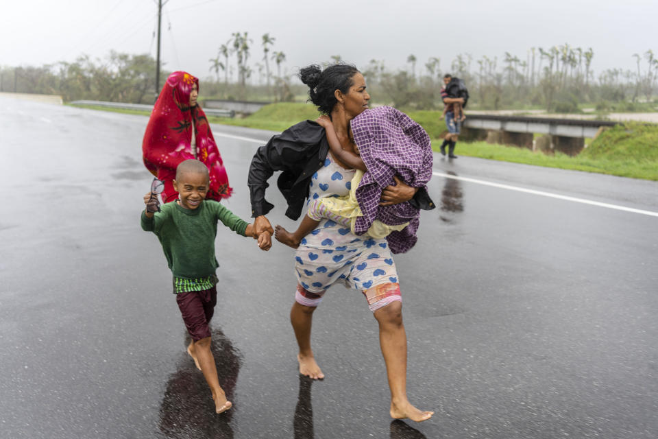 Una familia camina bajo la lluvia en búsqueda de un albergue el 27 de septiembre de 2022, luego de que el huracán Ian inundó su vivienda, en Pinar del Río, Cuba. (AP Foto/Ramón Espinosa)