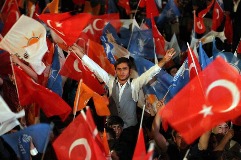 Supporters of the Justice and Development Party (AKP) wave flags and shout slogans as Turkish Prime Minister Recep Tayyip Erdogan delivers a speech in Ankara on June 7, 2015