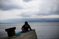 Kamel Purba, a farmer who lost his mother and brother in the ferry accident at Lake Toba, sits on a pier of Tigaras port in Simalungun, North Sumatra, Indonesia June 21, 2018. REUTERS/Beawiharta