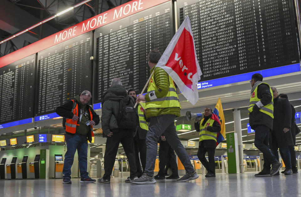 Airport employees in strike vests are on the move in Departure Hall B in Terminal 1 of Frankfurt Airport in Munich, Germany, Friday, Feb. 17, 2023. Thousands of flights to and from German airports were canceled Friday as workers walked out to press their demands for inflation-busting pay increases. The strikes at seven German airports, including Frankfurt, Munich and Hamburg, affected almost 300,000 passengers and forced airlines to cancel more than 2,300 flights. (Arne Dedert/dpa via AP)