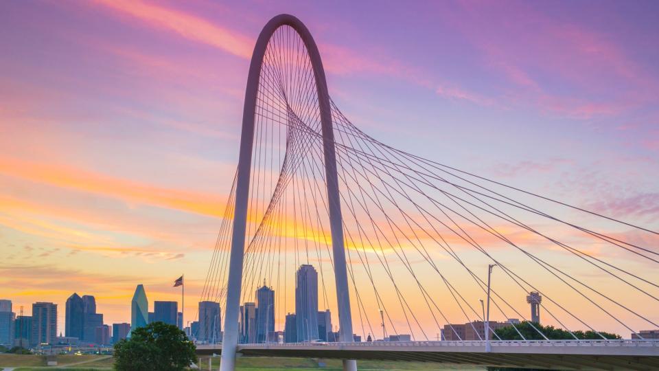 Margaret Hunt Hill Bridge with Downtown Dallas skyline at sunrise in Dallas, Texas.