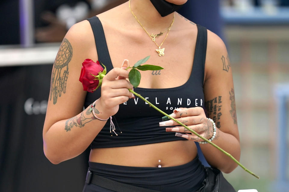 A waitress holds a rose given to her by a street vendor at the Clevelander Hotel and Bar on Ocean Drive, Friday, Sept. 24, 2021, in Miami Beach, Fla. For decades, this 10-block area has been one of the most glamorized spots in the world, made cool by TV shows like Miami Vice, where the sexiest models gathered at Gianni Versace's ocean front estate and rappers wrote lines about South Beach's iconic Ocean Drive. (AP Photo/Lynne Sladky)
