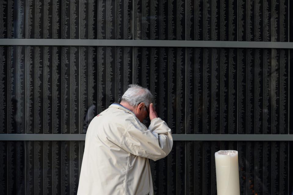 In this picture amde available Wednesday April 17, 2013 a man touches his forehead in front of the Victims' Memorial Wall during a ceremony in the Holocaust Memorial Centre in Budapest, Hungary, Tuesday, April 16 2013. (AP Photo/MTI, Tamas Kovacs)