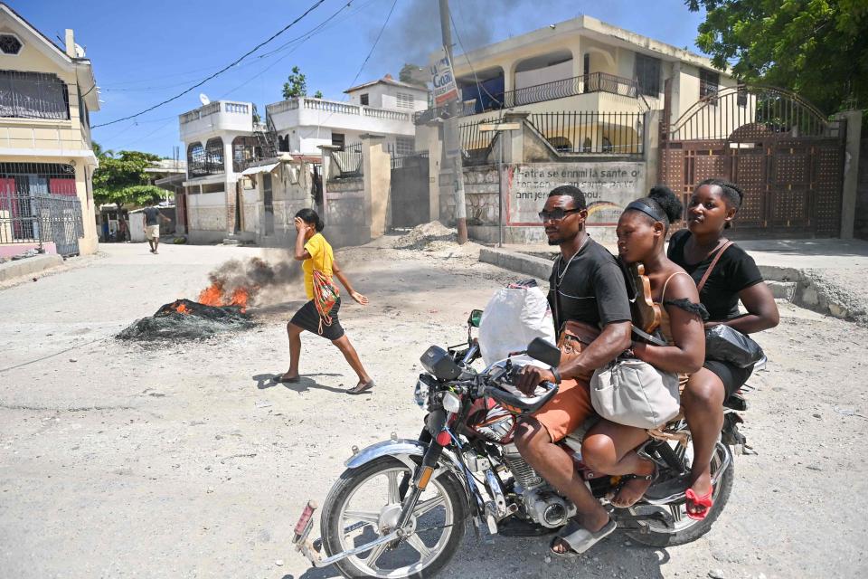 A motorcyclist passes by burning tires as people demonstrate over the rise in the cost of living in Petit-Goave, Haiti, on Sept. 14, 2023.