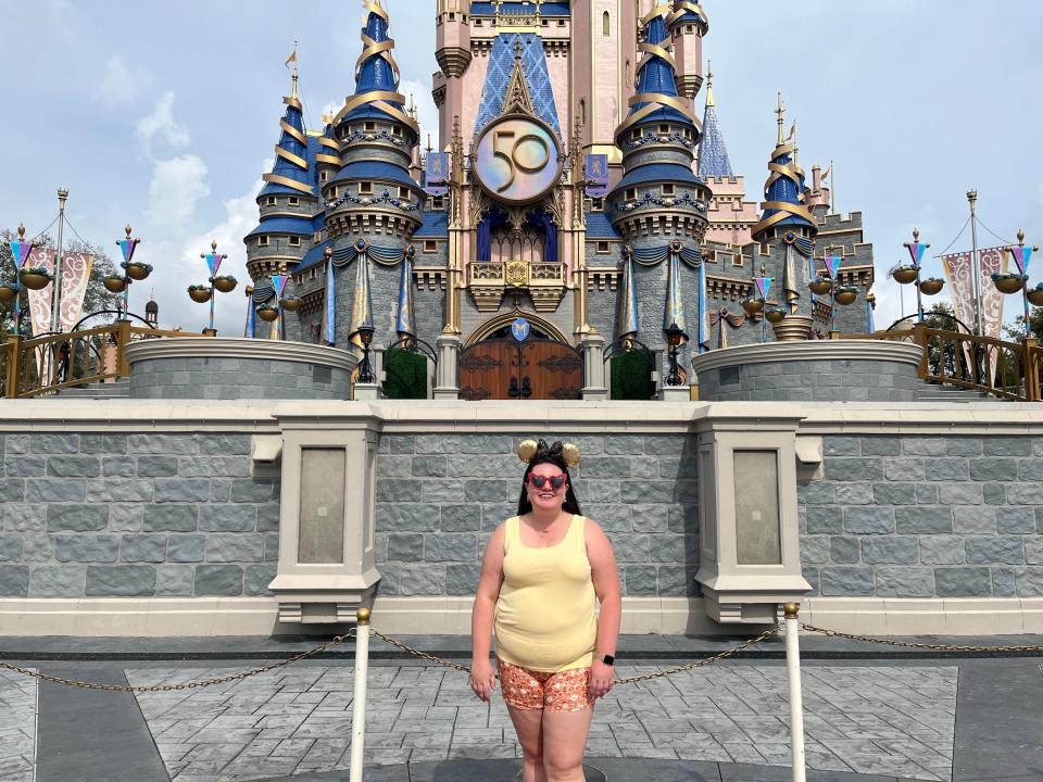 megan posing in front of cinderella castle decorated for the disney world 50th anniversary celebration