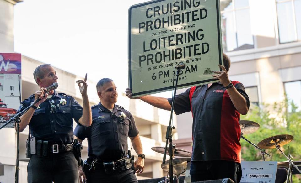 Modesto Police Chief Brandon Gillespie and assistant chief Ivan Valencia talk about ending the cruising ban as Chris Murphy holds the defunct cruising ban sign during the Legends of the Cruise inductees celebration at Tenth Street Plaza in Modesto, Calif., Wednesday, June 5, 2024.