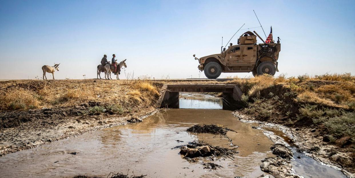 topshot   youths ride donkeys near a us military vehicle crossing a stream polluted by an oil spill near the village of sukayriyah, in the countryside south of rumaylan rmeilan in syrias kurdish controlled northeastern hasakeh province, on july 19, 2020   oil pollution in syria has become a growing concern since the 2011 onset of a civil war that has taken a toll on oil infrastructure and seen rival powers compete over control of key hydrocarbon fields in the kurdish held northeast, a large storage facility in the rmeilan oil field in hasakeh province is of particular concern, with leaks from the gir zero storage facility have been suspected since at least 2014, and the latest just in march 2020 photo by delil souleiman  afp photo by delil souleimanafp via getty images