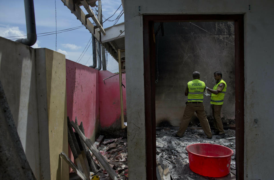 Police officers collect evidence from a site of a gun battle between troops and suspected Islamist militants in Kalmunai, Sri Lanka, Sunday, April 28, 2019. Police in Ampara showed The Associated Press on Sunday the explosives, chemicals and Islamic State flag they recovered from the site of one security force raid in the region as Sri Lanka's Catholics celebrated at televised Mass in the safety of their homes. (AP Photo/Gemunu Amarasinghe)