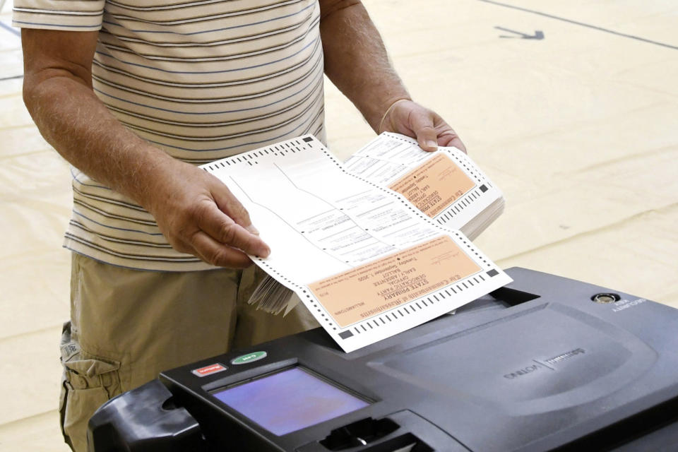 FILE - In this Tuesday, Sept. 1, 2020 photo, an election worker inserts mail-in ballots into a voting machine at a school in Williamstown, Mass., during the state's primary election. On Friday, Oct. 2, 2020, The Associated Press reported on stories circulating online incorrectly asserting that Massachusetts destroyed over 1 million primary ballots and committed election fraud. No physical Senate ballots have been destroyed in Massachusetts, according to Debra O’Malley, a spokesperson for Secretary of the Commonwealth of Massachusetts William Galvin. A federal statute requires election officials to preserve ballots from federal races for 22 months. (Gillian Jones/The Berkshire Eagle via AP)