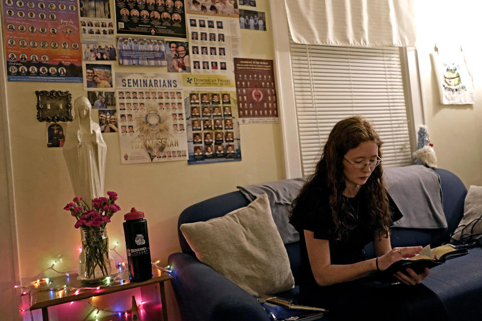 Benedictine College student Niki Wood looks through her prayer book before evening prayers with her roommates in the house they share Sunday, Dec. 3, 2023, in Atchison, Kan. (AP Photo/Charlie Riedel)