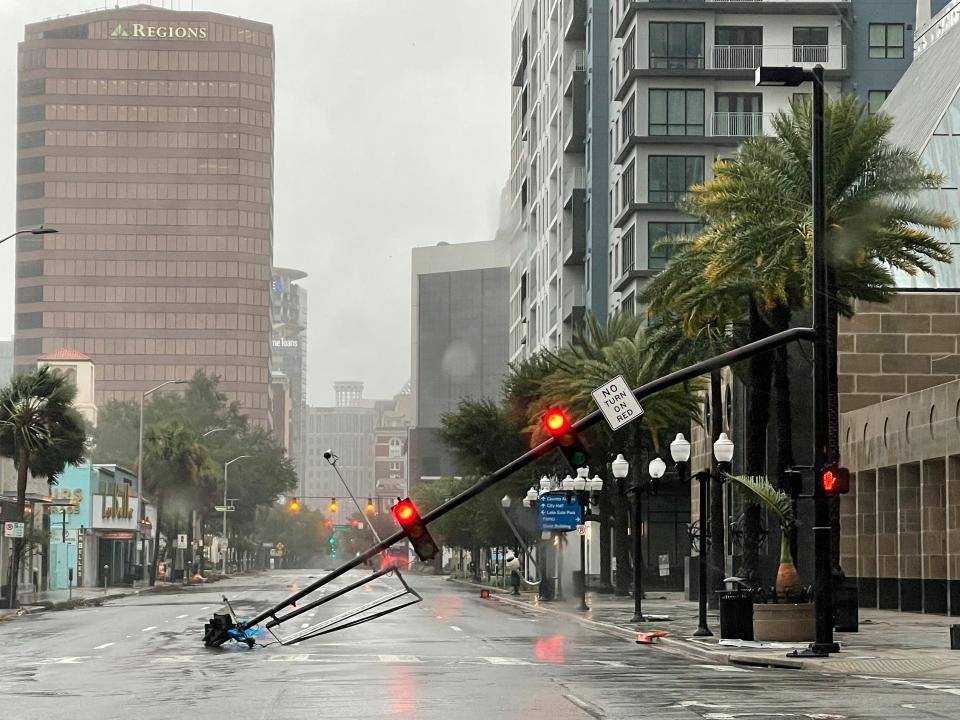 A stoplight pole blown down by Hurricane Ian winds, rests on Orange Avenue in Downtown Orlando, Fla., on Thursday, Sept. 29, 2022.   Hurricane Ian has left a path of destruction in southwest Florida, trapping people in flooded homes, damaging the roof of a hospital intensive care unit and knocking out power. (Willie J. Allen Jr./Orlando Sentinel via AP)