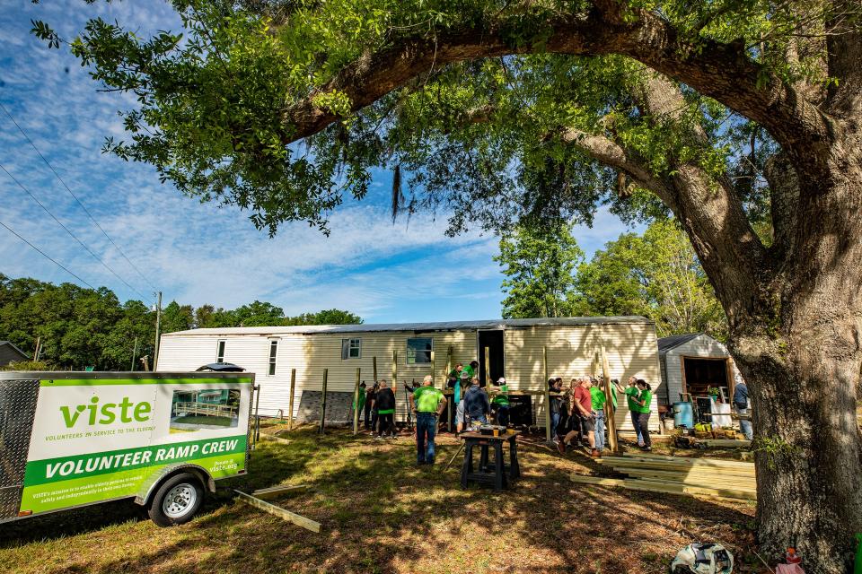 Volunteers from Publix and VISTE work to install a deck and ramp at the home of the Persaud family in the Kathleen area. Habitat For Humanity is contributing to the renovation of the single-wide mobile home.