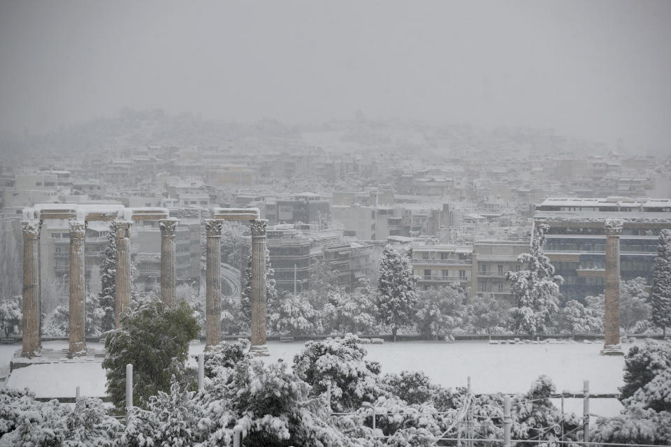 Snow covers the ancient temple of Zeus in Athens, Tuesday, Feb.16, 2021. Unusually heavy snowfall has blanketed central Athens, with authorities warning residents particularly in the Greek capital's northern and eastern suburbs to avoid leaving their homes. (AP Photo/Thanassis Stavrakis)