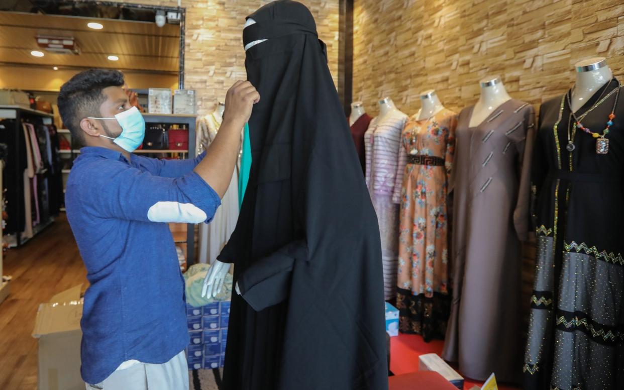  A Sri Lankan shop worker puts burqa on a mannequin at his garment shop in Colombo, Sri Lanka, - Shutterstock /Shutterstock 