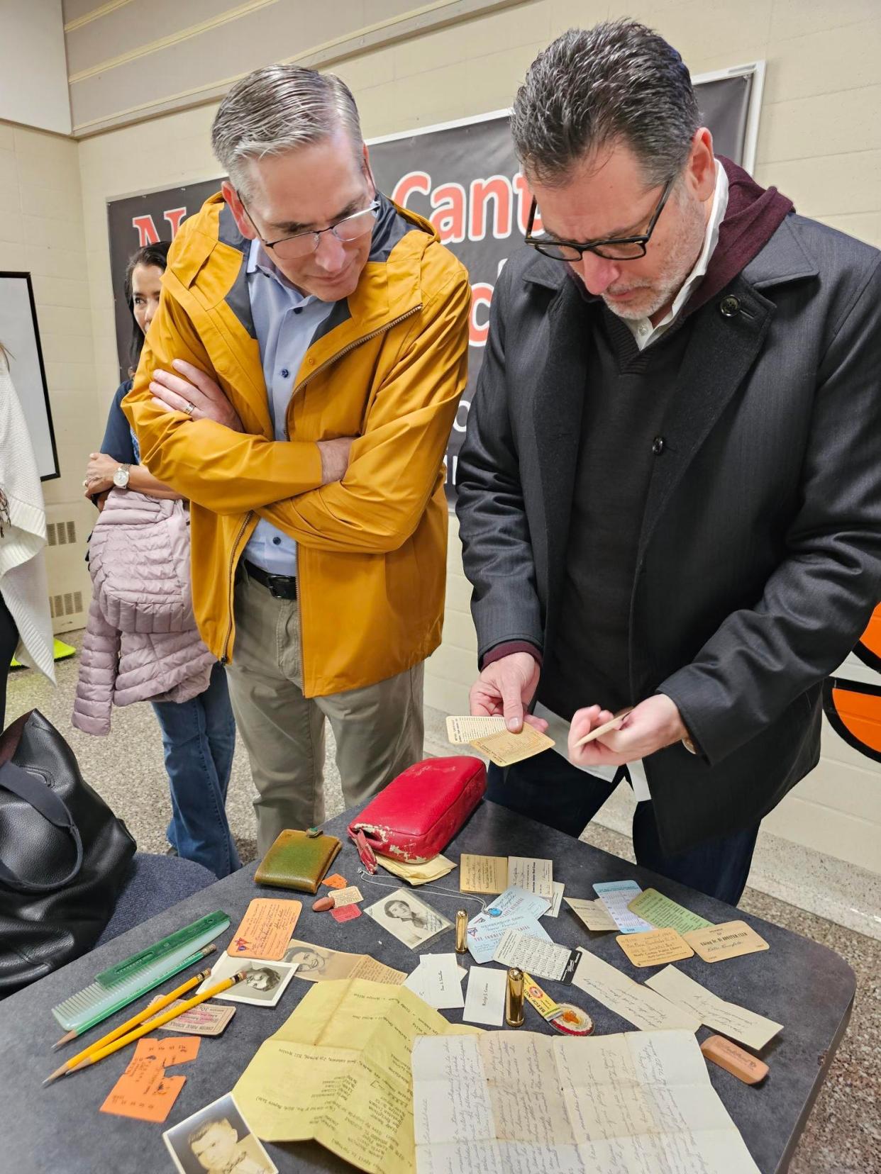 Emory, left, and Charles Anderson look over black and white photos, newspaper clippings, membership cards and other items found in a purse owned by their mother Patti Rumfola. While a student at Hoover High School in the late 1950s, Rumfola's purse was lost between a wall and a set of lockers.