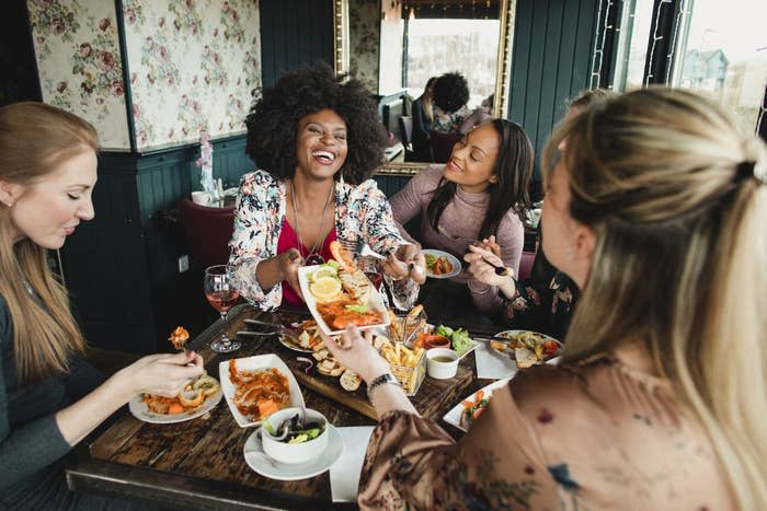 Group of young women sitting at a restaurant table eating