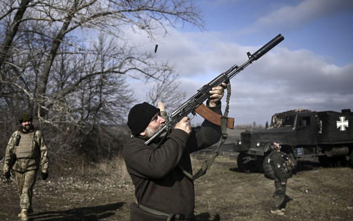 A Ukrainian serviceman shoots with his rifle at a drone near Bakhmut - ARIS MESSINIS/AFP