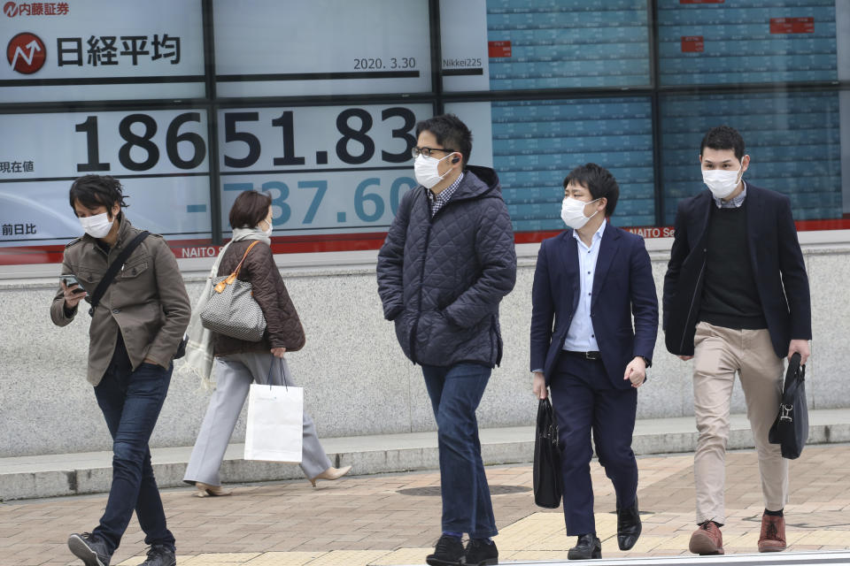 People walk by an electronic stock board of a securities firm in Tokyo, Monday, March 30, 2020. Asian shares started the week with further losses as countries reported surging numbers of infections from the coronavirus that has prompted shutdowns of travel and business in many parts of the world. (AP Photo/Koji Sasahara)