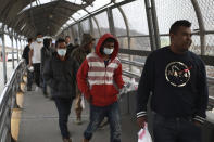 FILE - In this March 21, 2020 file photo, Central American migrants seeking asylum, some wearing protective face masks, return to Mexico via the international bridge at the U.S-Mexico border that joins Ciudad Juarez and El Paso. Vice President Mike Pence in March directed the nation’s top disease control agency to use its emergency powers to effectively seal the U.S. borders, overruling the agency’s scientists who said there was no evidence the action would slow the coronavirus, according to two former health officials. (AP Photo/Christian Chavez, File)