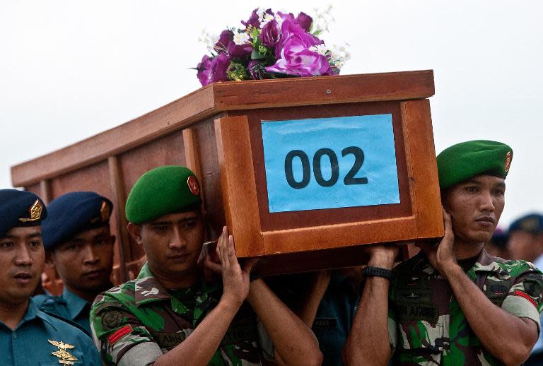 Indonesian military personnel carry the coffin of a victim recovered from the ill-fated Malaysian air carrier AirAsia flight QZ8501, upon their arrival at the military airbase in Surabaya, East Java, on December 31, 2014