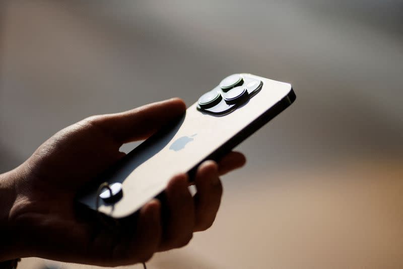 FILE PHOTO: A man holds an iPhone 14 as Apple Inc's new models go on sale at an Apple store in Beijing