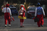 La payasa Sara Olazábal, cuyo nombre de actuación es "Chiquilina", camina entre sus hermanos Alan "Chiquilín", a la izquierda, y Michel "Chiquitín Jr." a una casa donde realizarán un espectáculo al aire libre y los niños mirarán a través de las ventanas, en un barrio pobre en las afueras de Lima, Perú, el lunes 20 de julio de 2020. (AP Foto/Martín Mejía)